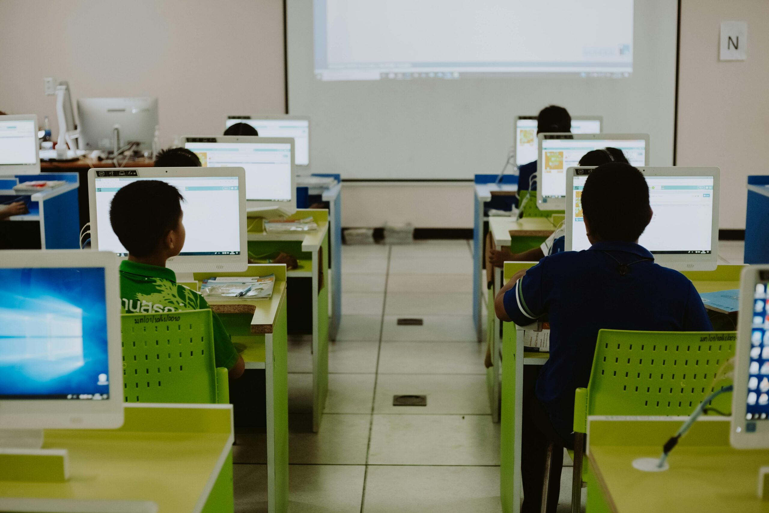Children focus on computers in a modern classroom setting.